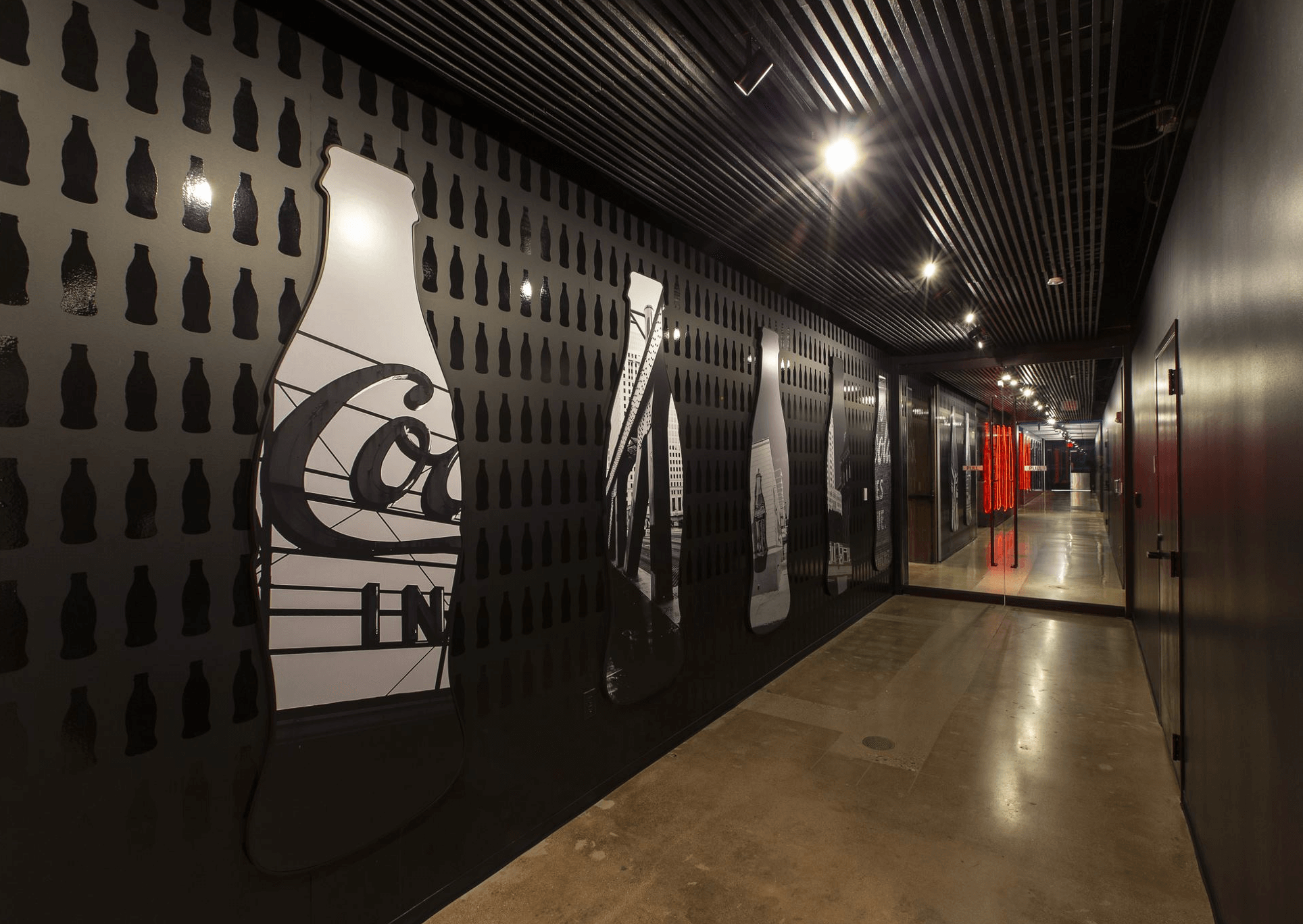 coca-cola bottles line a long hallway in black and white images and neon shapes