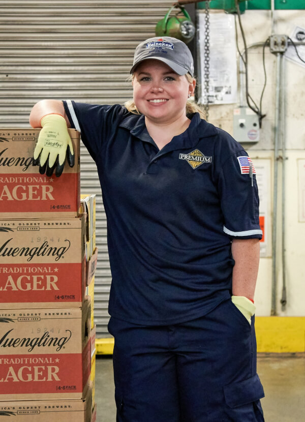 Happy young woman leans on stack of Yuengling Beer in customer account