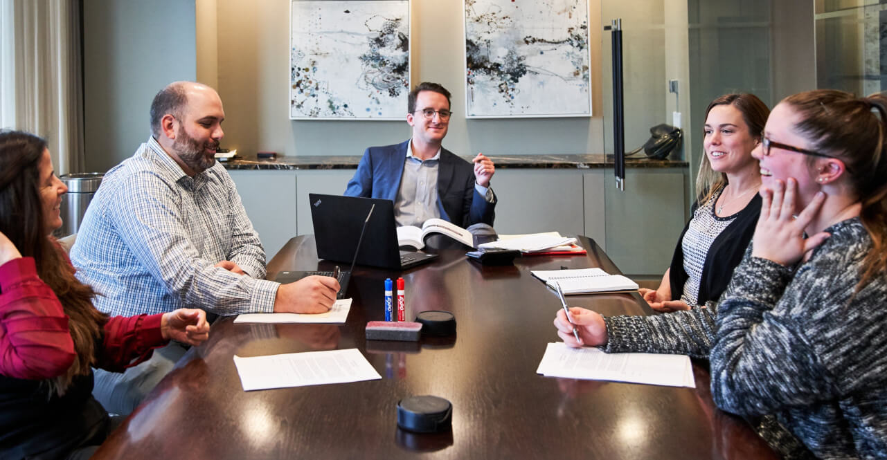 Group of Reyes Holdings employees sit in conference meeting laughing at a joke