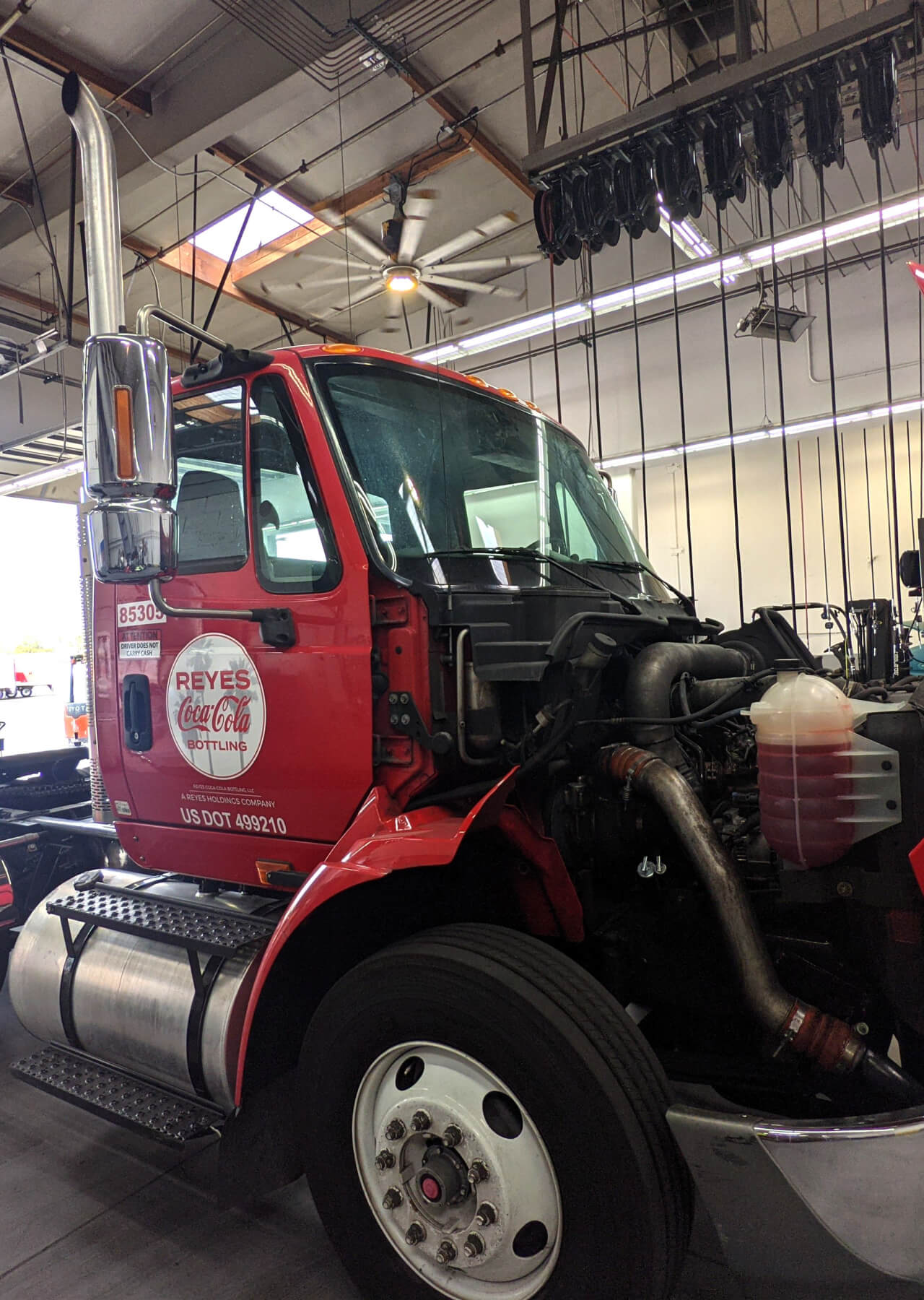 Reyes Coca-Cola truck sits in fleet shop with front of truck disassembled for repairs