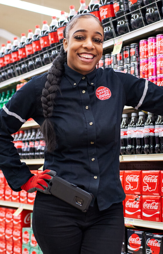 Smiling girl standing by Coca-Cola shelf