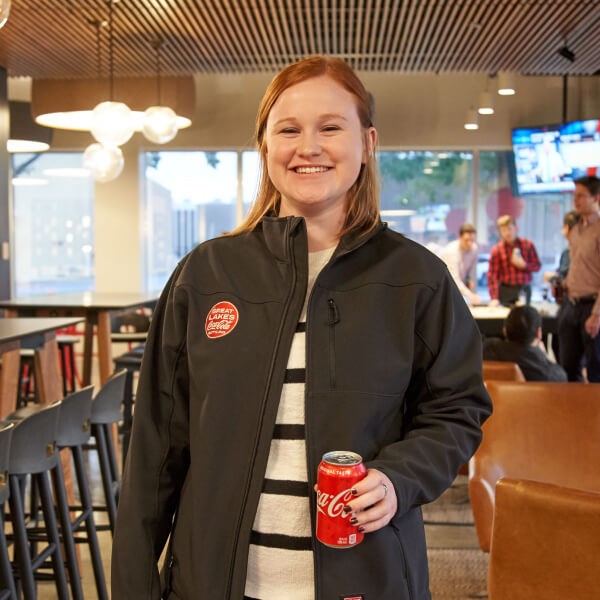 Smiling girl wearing Great Lakes Coca-Cola uniform and holding a Coca-Cola can