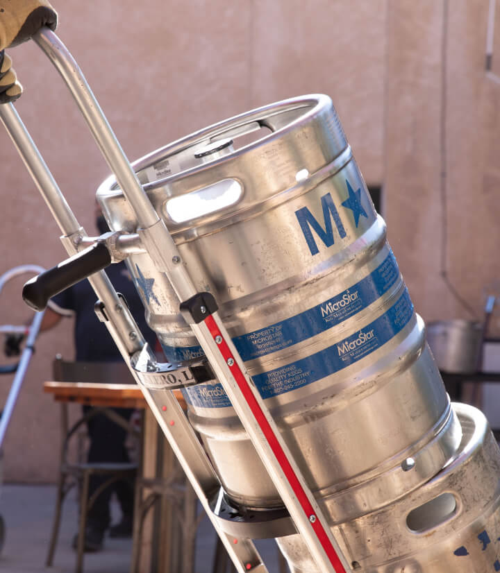 Two metal beer kegs stored on top of each other on the dolly