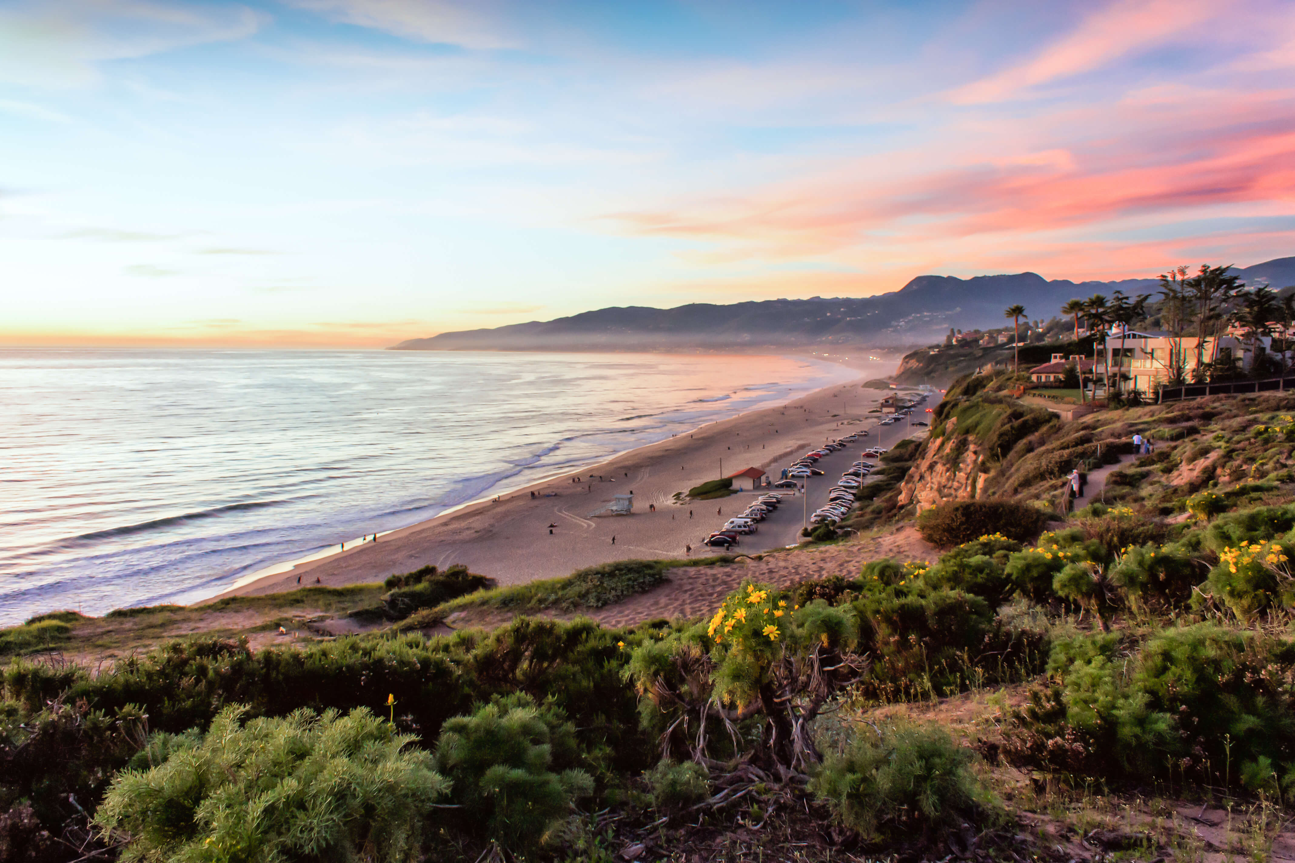 Sunset on the beach of malibu from overlooking grassy cliff