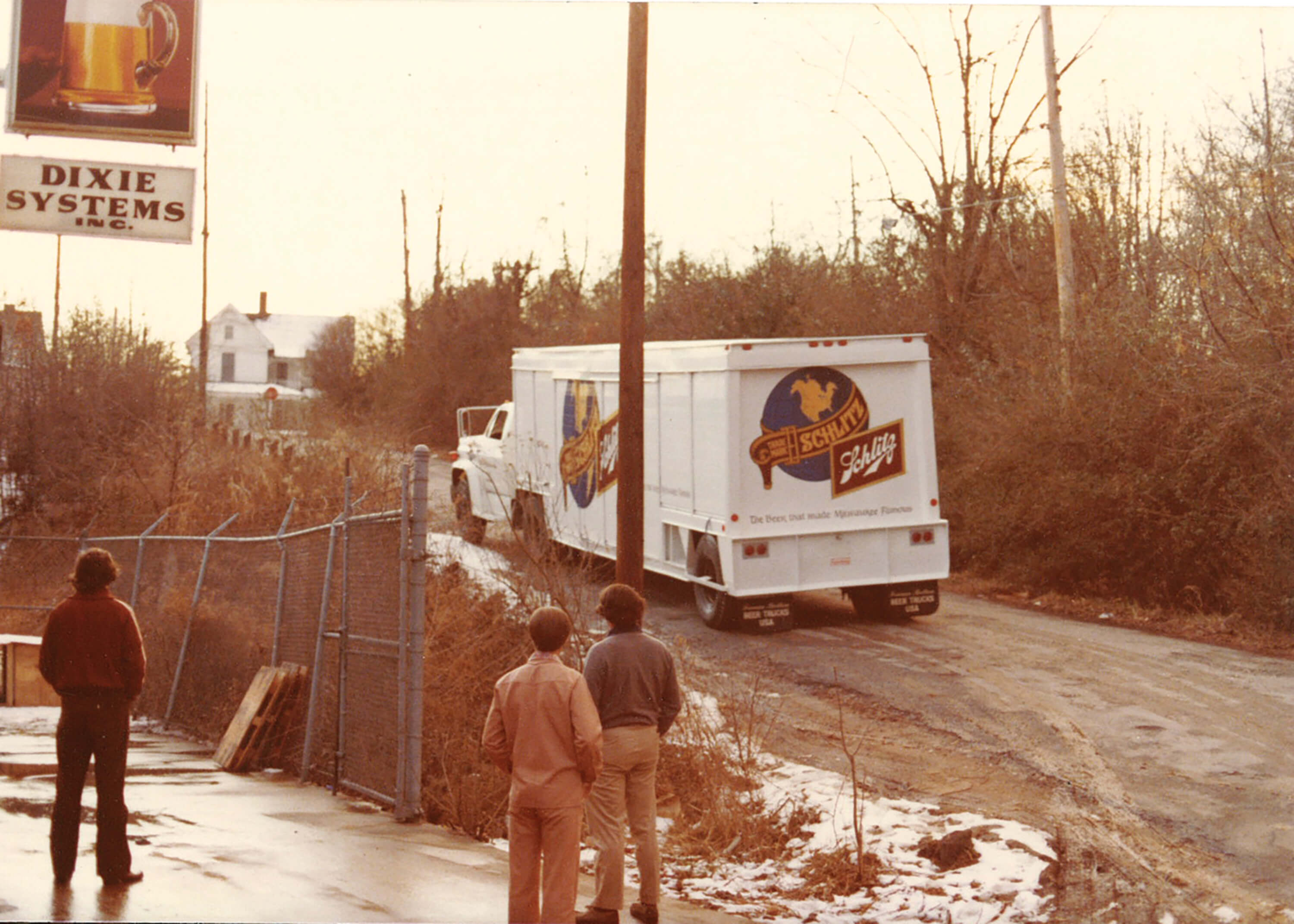 vintage photo of three men watching Schlitz beer delivery truck drive away